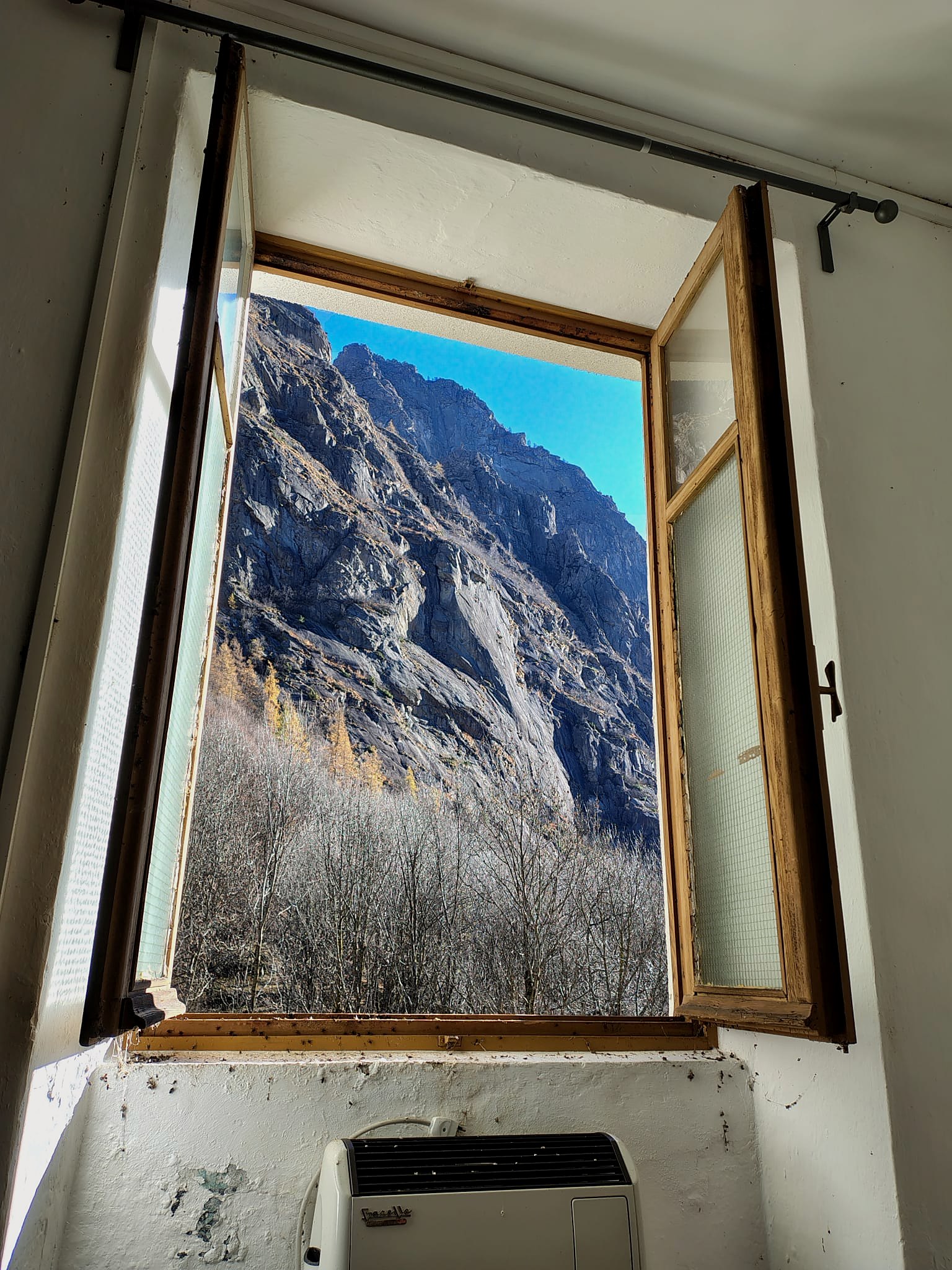 Finestra aperta dall'interno dell'edificio di Tressi sui versanti innevati della valle
