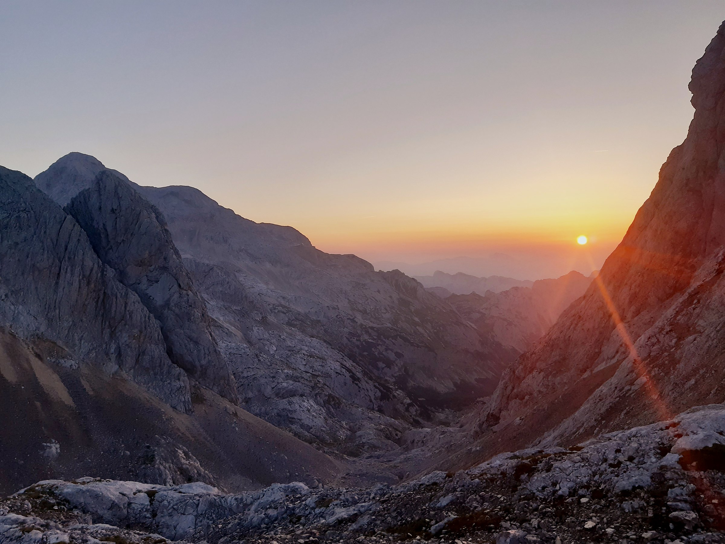 Il vallone all'alba, tra pareti rocciose e prime luci sulle cime