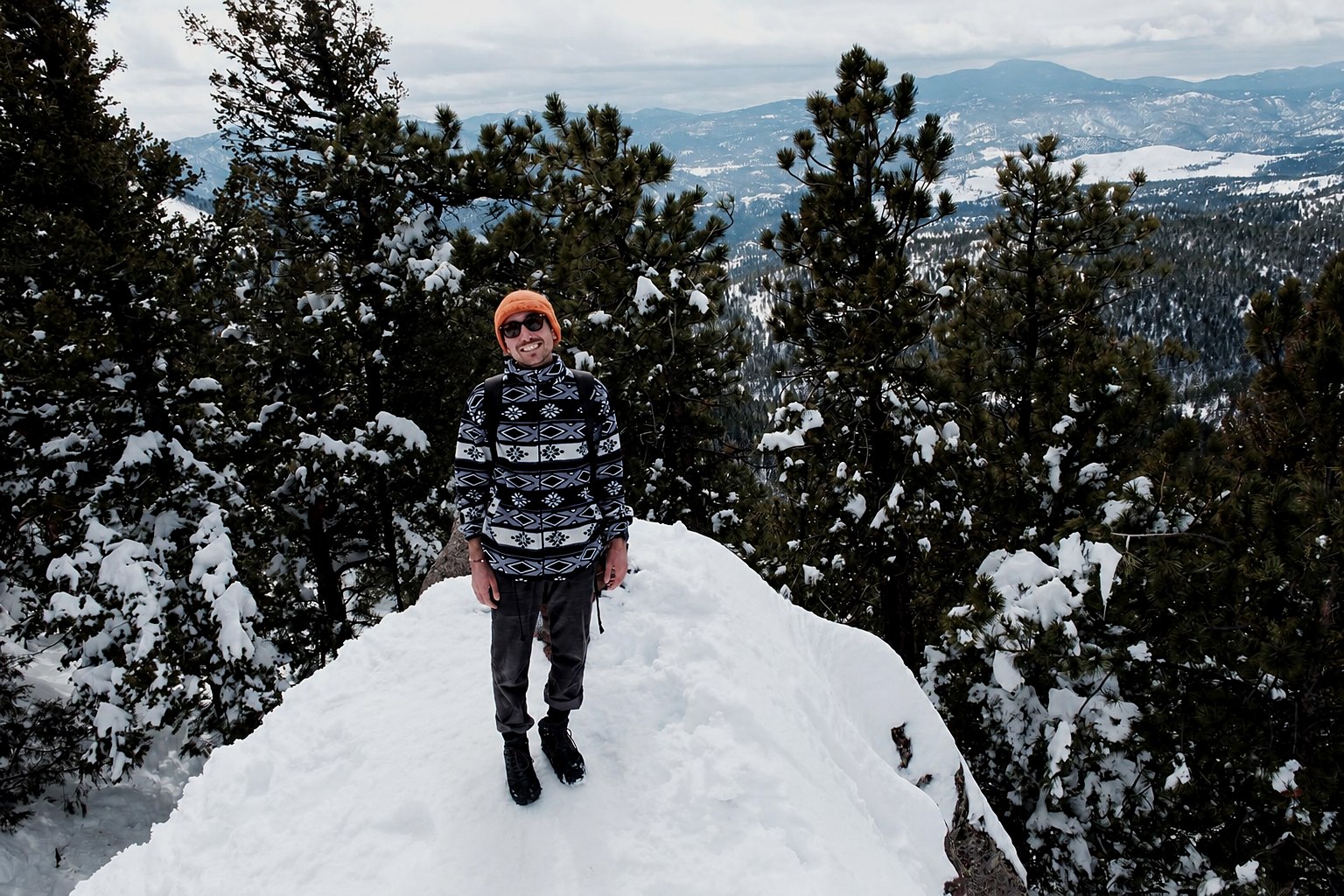 Andrea Vito Vacca in piedi sulla neve, tra i larici del versante